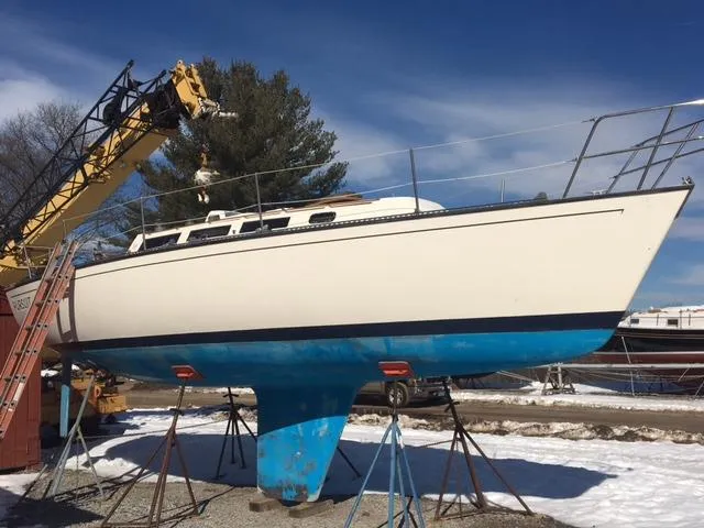 Slide: The Image of 1985 S2 9.1 sailboat on stands, undergoing maintenance in a snowy boatyard. - 1