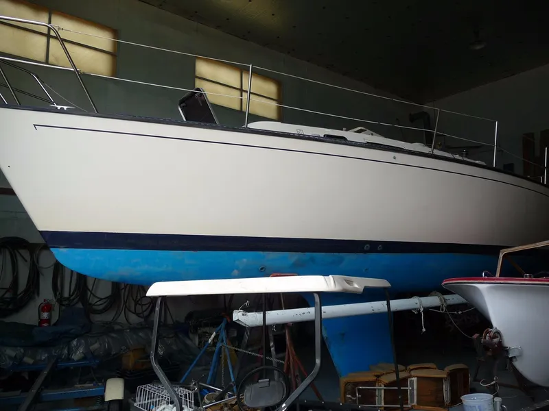 Slide: The Image of 1985 S2 9.1 sailboat in indoor storage, white hull with blue bottom paint. - 15