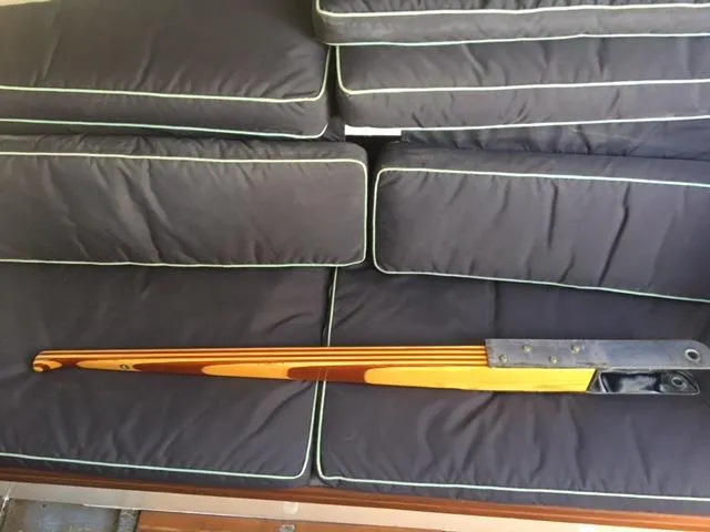 Slide: The Image of Vintage S2 9.1 1985 wooden sailboat tiller on black cushioned seating. - 7