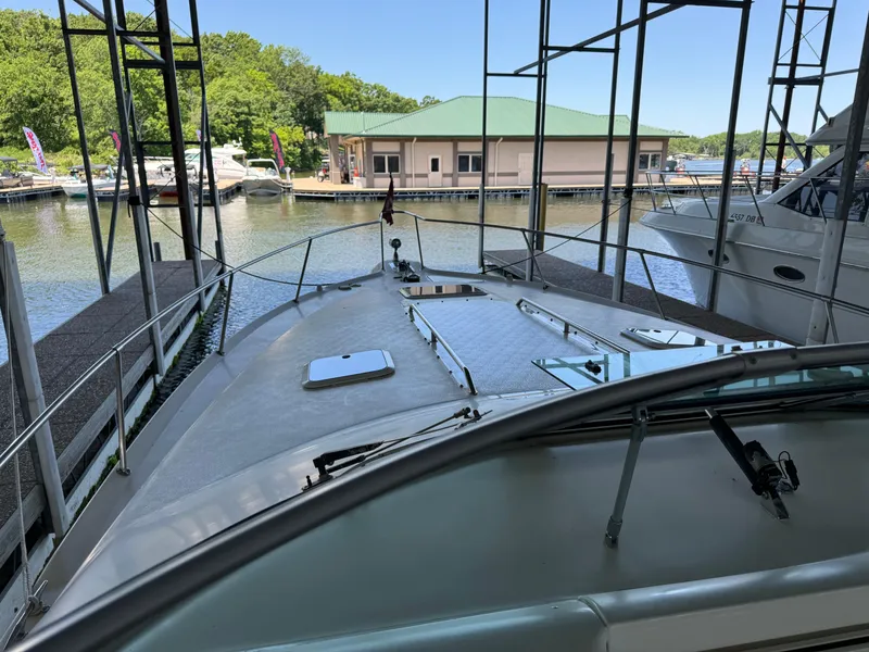 Slide: The Image of 1998 Sea Ray 330 Sundancer docked at a marina with green-roofed building in background. - 15