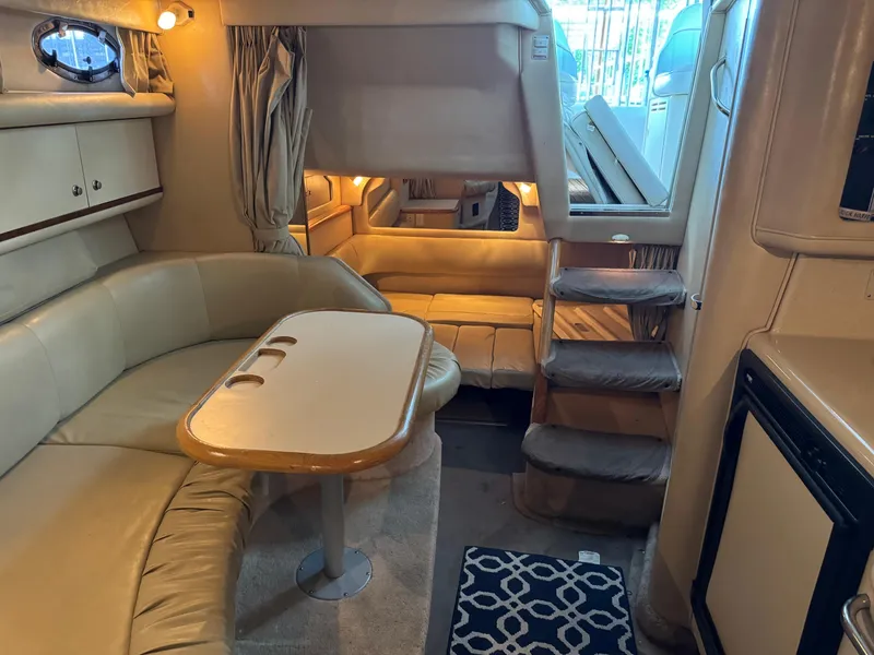 Slide: The Image of Interior of a 1998 Sea Ray 330 Sundancer yacht with beige seating and a dining table. - 18