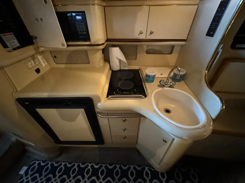 Slide: The Image of 1998 Sea Ray 330 Sundancer galley with sink, stove, and mini-fridge. - 21