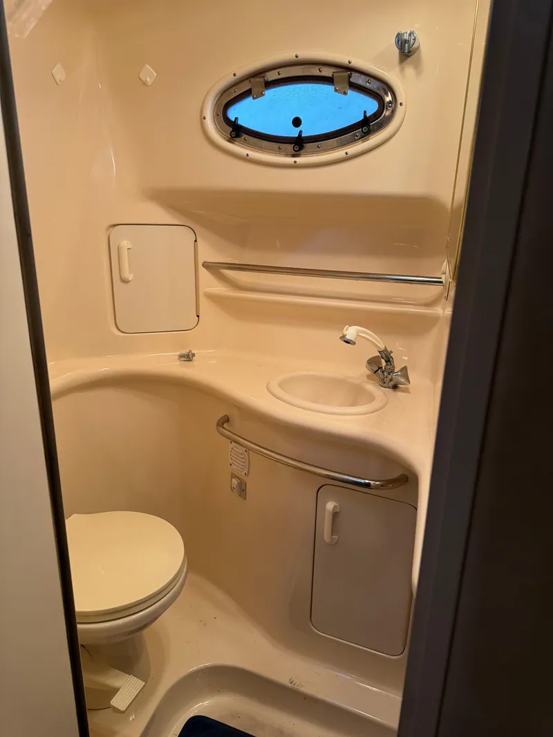 Slide: The Image of 1998 Sea Ray 330 Sundancer bathroom with sink, toilet, and porthole window. - 23
