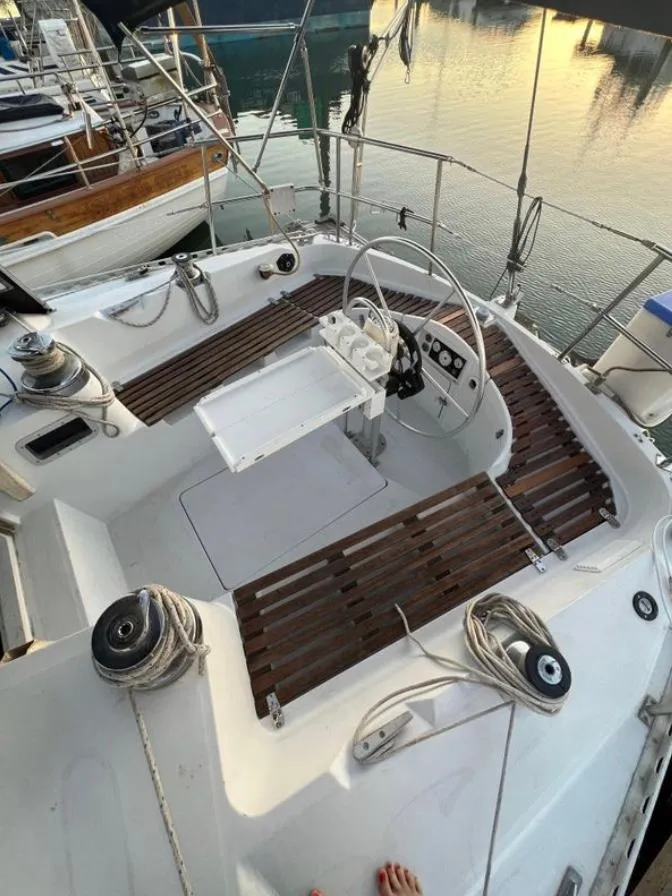 Slide: The Image of 1985 Gib'Sea 126 sailboat cockpit with wooden seating and steering wheel, docked at sunset. - 18