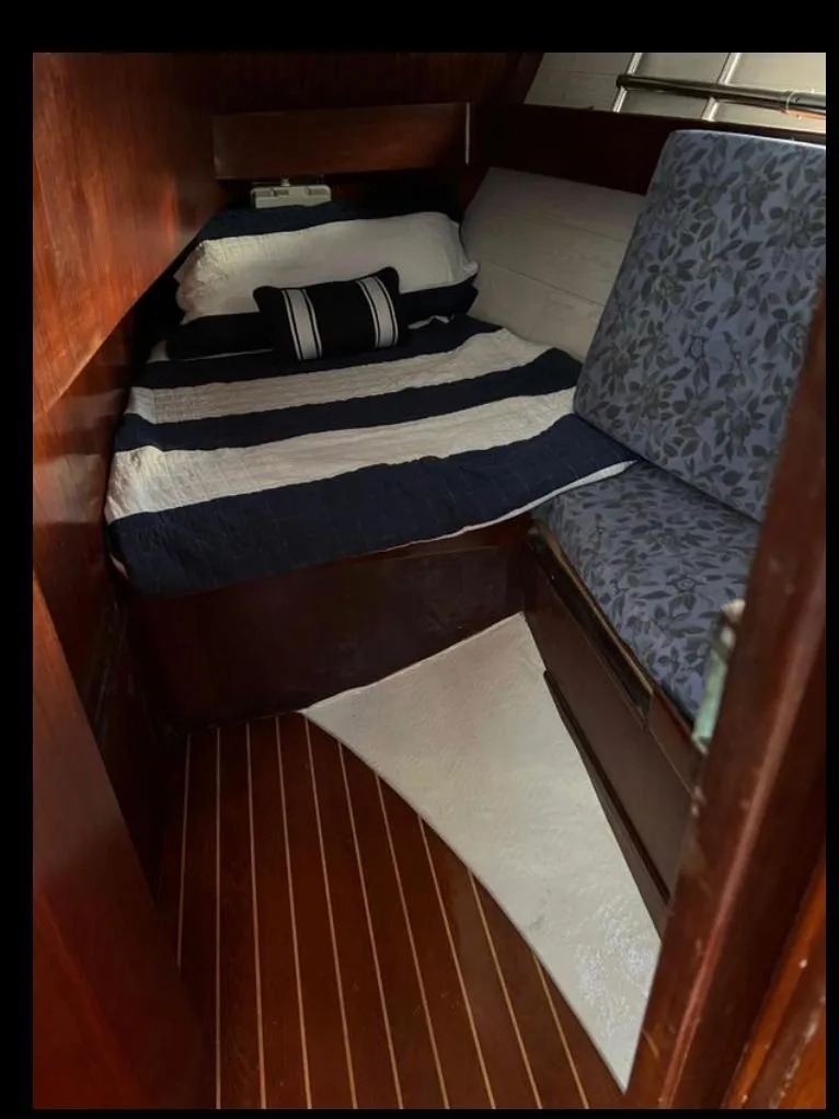 Slide: The Image of Cozy cabin interior of 1985 Gib'Sea 126 sailboat with striped bedding and wooden flooring. - 44