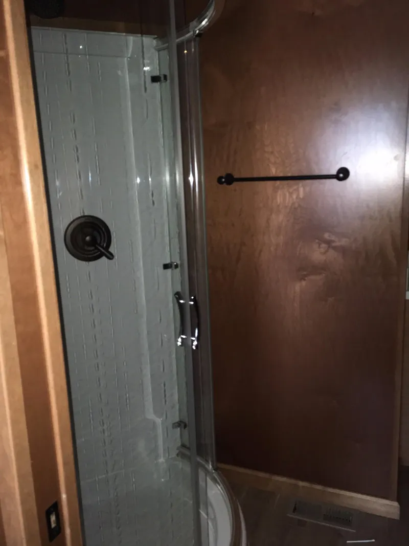 Slide: The Image of Shower area in 2014 Bravada Imagination Trip #15 RV, featuring glass door and wooden paneling. - 23