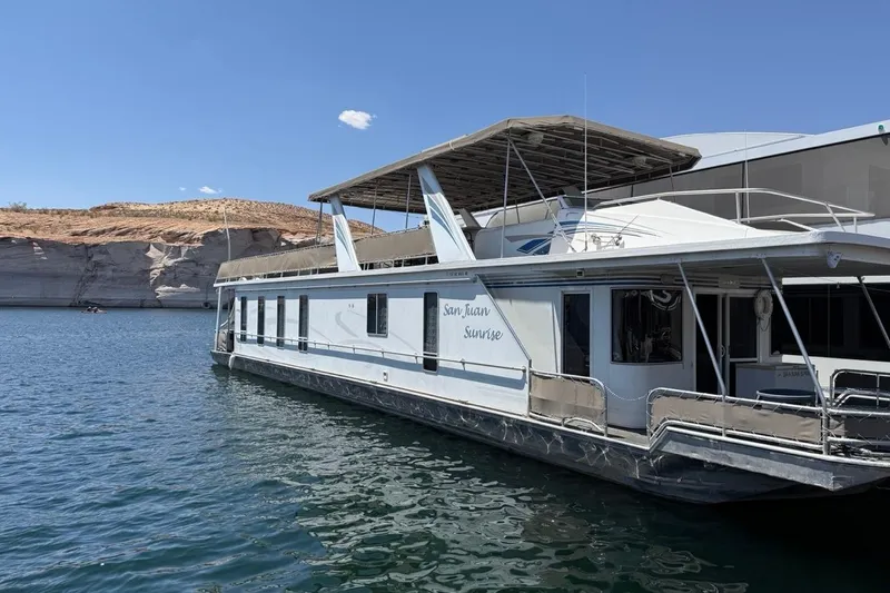 The Image of 2004 Sharpe Houseboat San Juan Sunrise on serene lake with rocky shoreline. - 1