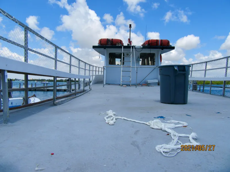 Slide: The Image of Commercial drift fishing boat deck with ropes, trash bin, and life preservers under a blue sky. - 13