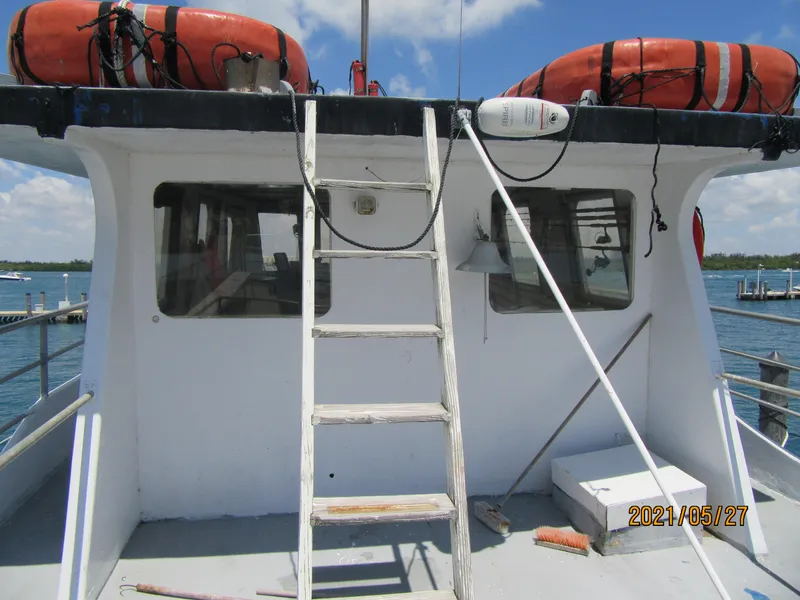 Slide: The Image of Commercial fishing boat with life preservers, ladder, and windows, docked by the water. - 30