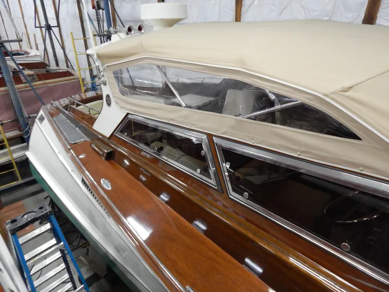 Slide: The Image of Classic 1990 Mays Craft 44 boat with wooden deck and beige canopy in storage. - 12