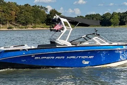 Slide: The Image of 2015 Nautique Super Air Nautique G25 boat cruising on a lake with trees in the background. - 5