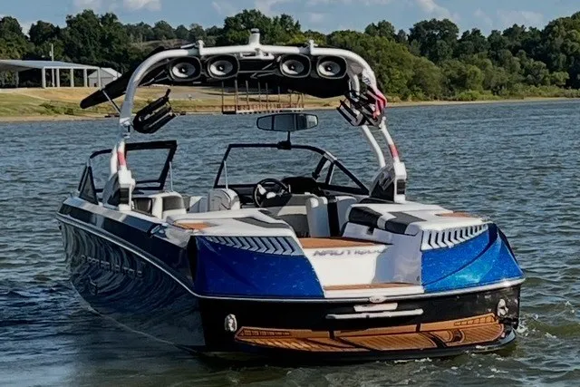 Slide: The Image of 2015 Nautique Super Air Nautique G25 boat on a lake with lush green shoreline. - 12