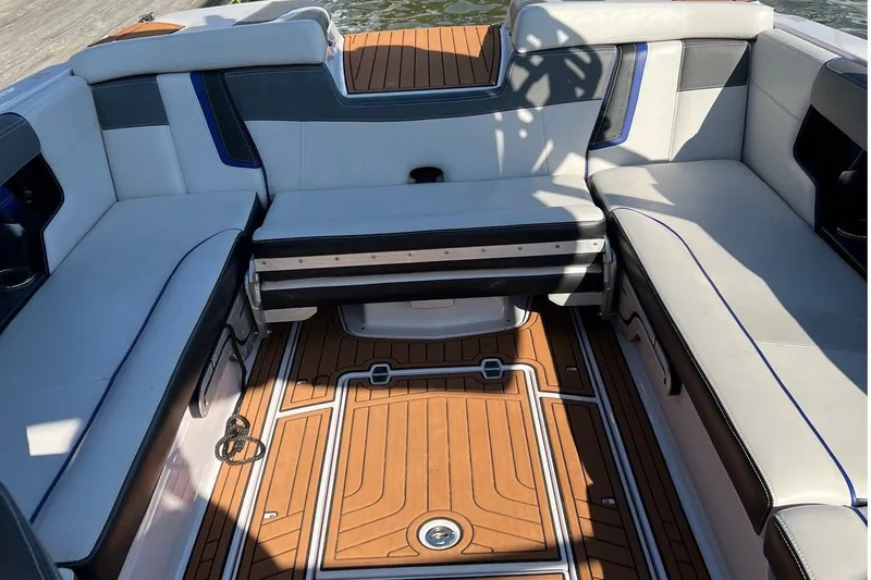 Slide: The Image of The image shows the interior of a 2015 Nautique Super Air Nautique G25 with sleek seating and wood flooring. - 9