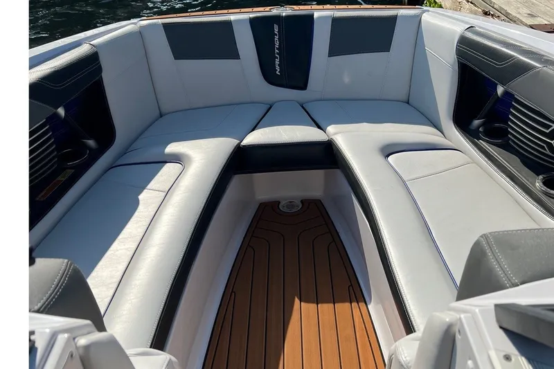 Slide: The Image of The image shows the bow area of a 2015 Nautique Super Air Nautique G25 with white upholstery and wood flooring. - 10