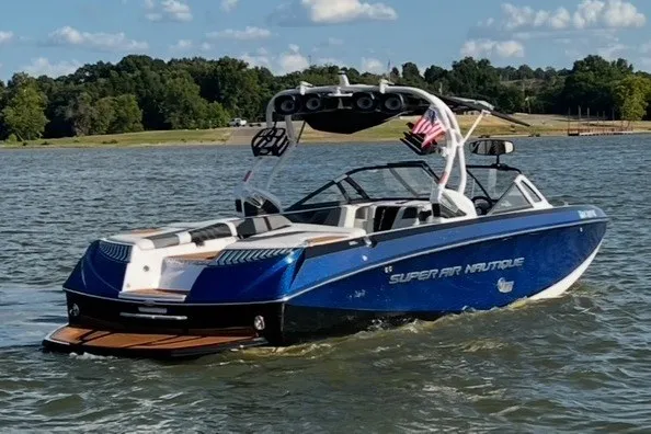 Slide: The Image of 2015 Nautique Super Air Nautique G25 boat cruising on a lake under a clear sky. - 4