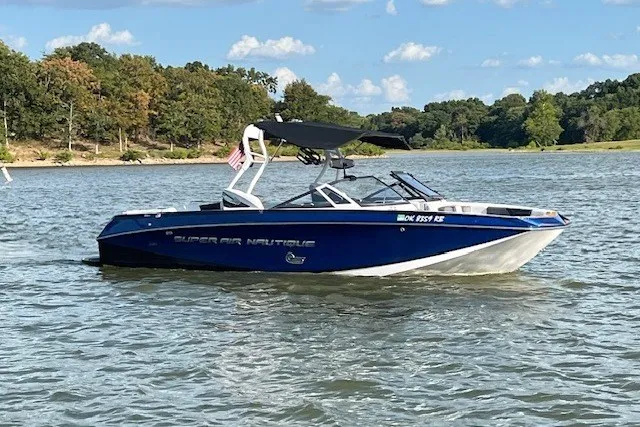 Slide: The Image of 2015 Nautique Super Air Nautique G25 boat on a lake with trees in the background. - 1