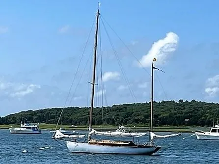 Slide: The Image of Alden Yawl 1938 sailboat anchored in a scenic bay with other boats. - 22