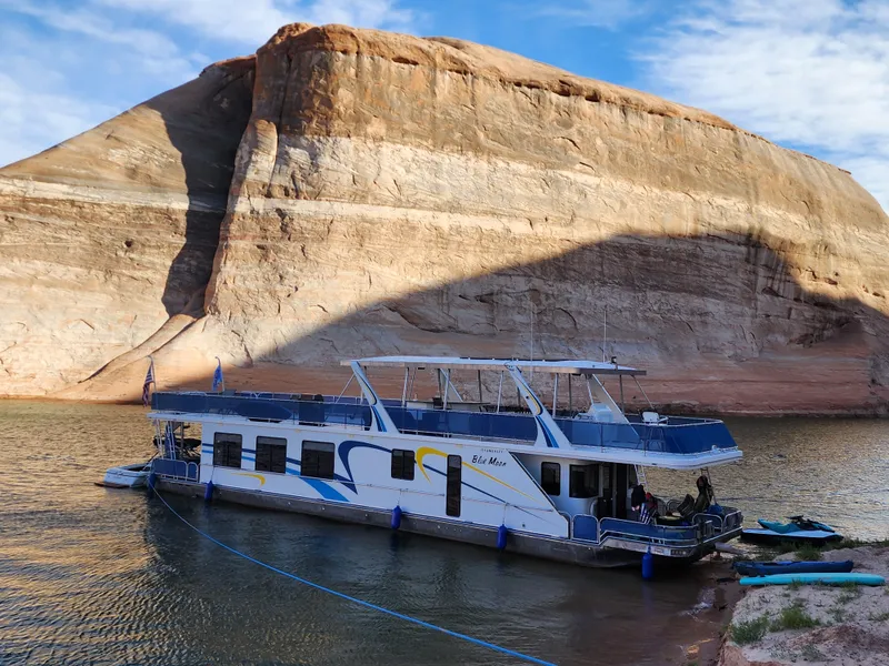 Slide: The Image of 2008 Sumerset Blue Moon houseboat docked by rocky shoreline under blue sky. - 10