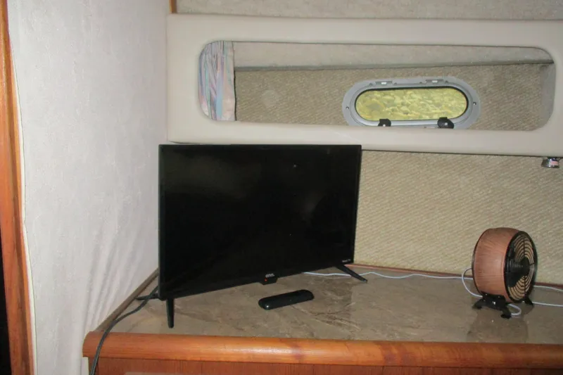 Slide: The Image of Interior of 1988 Bayliner 3888 Motoryacht with TV and fan on a wooden surface. - 18