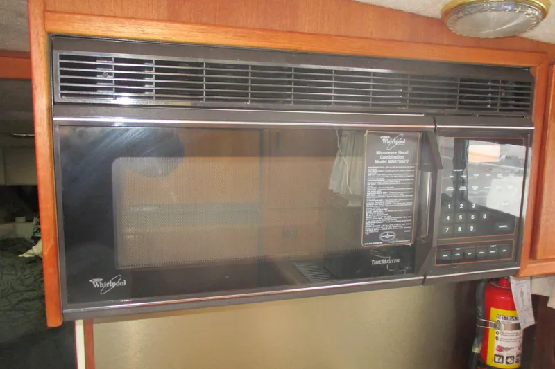 Slide: The Image of Whirlpool microwave in 1988 Bayliner 3888 Motoryacht kitchen, featuring digital controls and wood cabinetry. - 7