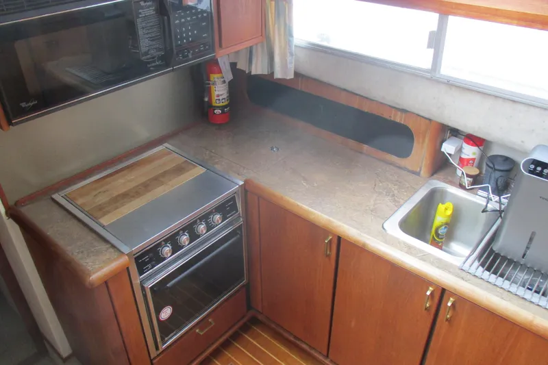 Slide: The Image of 1988 Bayliner 3888 Motoryacht kitchen with stove, sink, and wooden cabinetry. - 6
