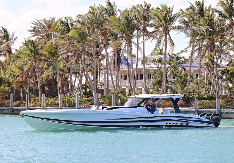 The Image of 2025 MTI V Marine Technology Inc V 57 boat cruising near palm trees and waterfront homes. - 0