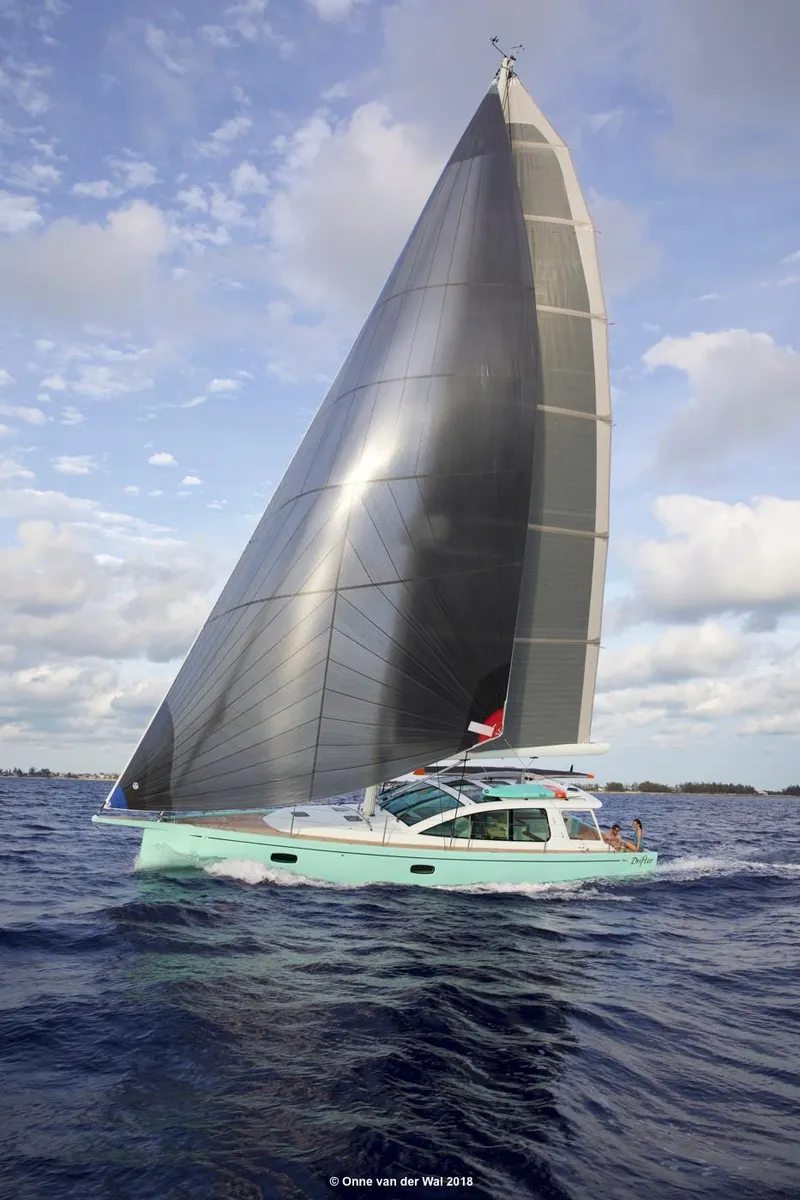Slide: The Image of Sleek 2025 Surfari 50 sailboat gliding on open water under a clear sky. - 0