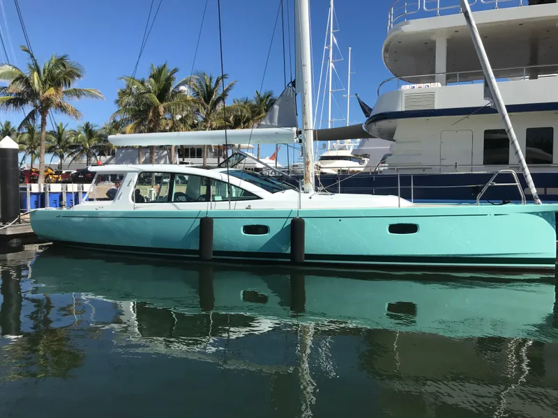 Slide: The Image of 2025 Surfari 50 yacht docked, turquoise hull, palm trees in background, sunny day. - 10