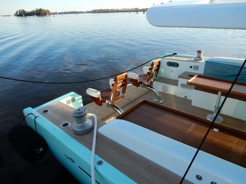 Slide: The Image of Luxurious 2025 Surfari 50 yacht deck with wooden seating, docked on calm waters. - 25