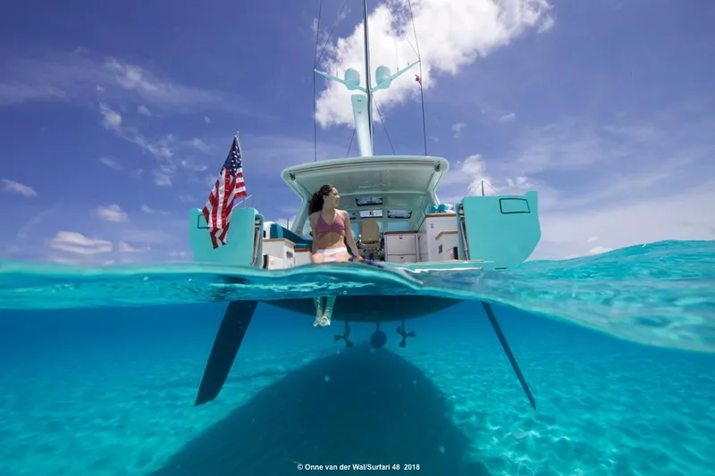 Slide: The Image of Woman relaxing on a 2025 Surfari 50 yacht, clear blue ocean, American flag waving. - 3