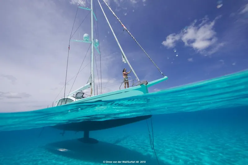 Slide: The Image of Sailboat Surfari 50, 2025 model, floating on clear blue water under a sunny sky. - 4