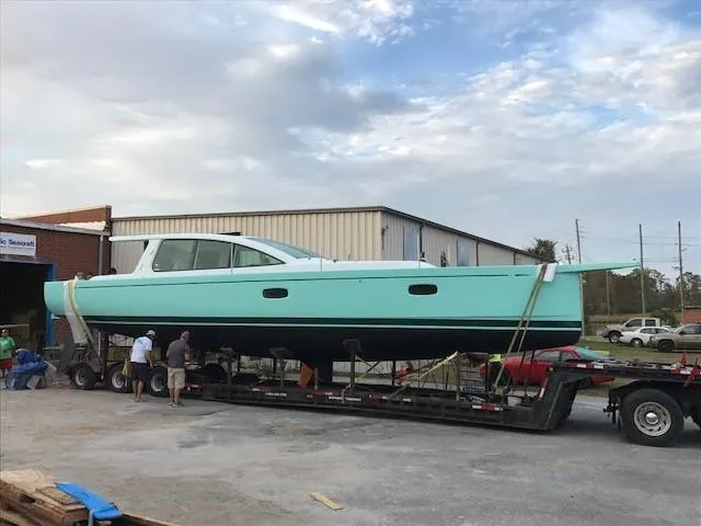 Slide: The Image of 2025 Surfari 50 yacht on trailer, turquoise hull, people inspecting, industrial background. - 7