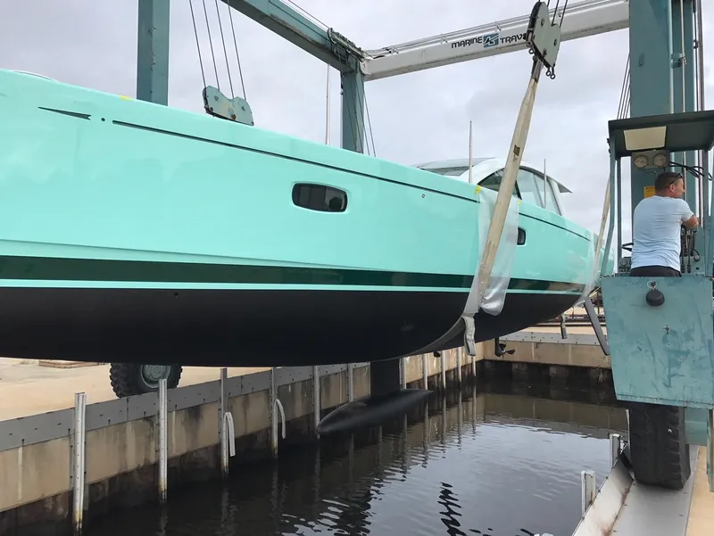 Slide: The Image of A 2025 Surfari 50 yacht being lifted by a crane at a marina. - 8