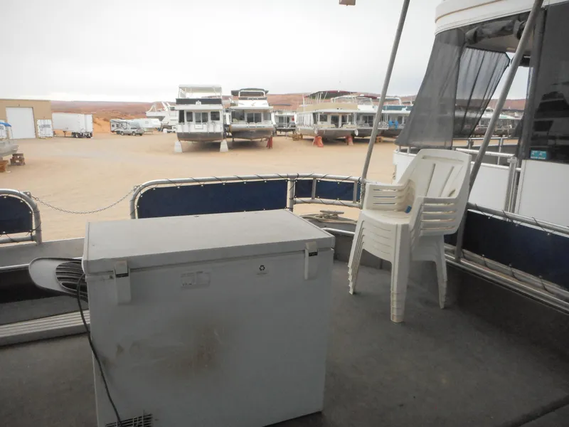 Slide: The Image of 2003 Stardust Cruisers Summer Haven Trip 33 houseboat docked with white chairs and cooler. - 25