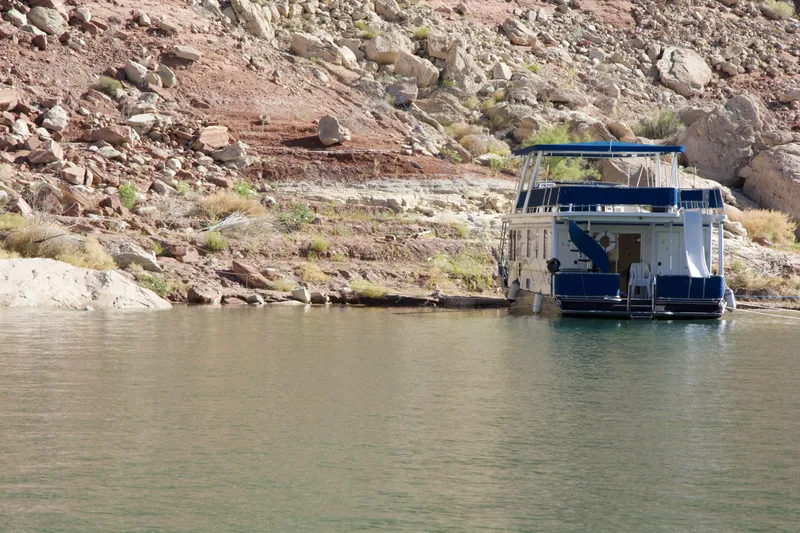Slide: The Image of Houseboat Stardust Cruisers Summer Haven Trip 33 docked by rocky shoreline, 2003 model. - 38