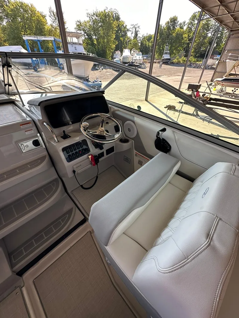Slide: The Image of 2025 Regal 26XO boat interior with steering wheel and seating in a marina setting. - 18