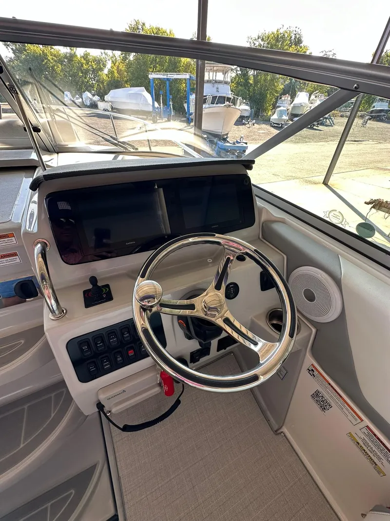 Slide: The Image of 2025 Regal 26XO boat interior with steering wheel and dashboard, docked outdoors. - 19