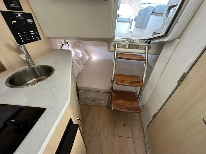 Slide: The Image of 2025 Regal 26XO boat interior with kitchenette, featuring microwave, sink, and storage. - 26