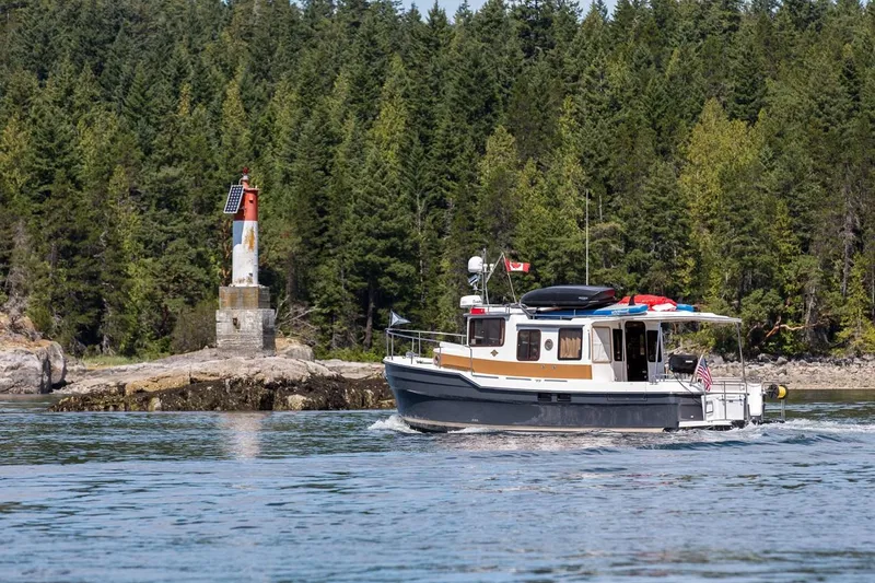 Slide: The Image of 2024 Ranger Tugs R-31 Sedan Luxury Edition cruising near a forested shoreline. - 12