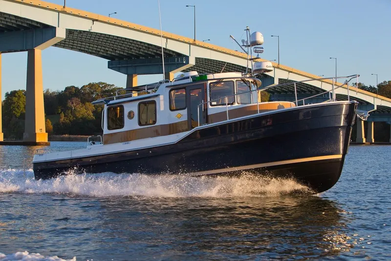 Slide: The Image of 2024 Ranger Tugs R-31 Sedan Luxury Edition cruising under a bridge. - 27
