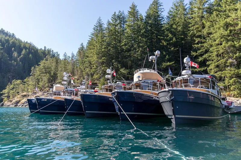 Slide: The Image of 2024 Ranger Tugs R-31 Sedan Luxury Edition boats docked in a scenic forested lake. - 5