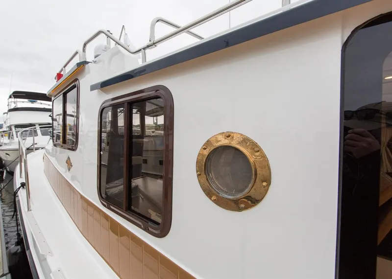 Slide: The Image of 2024 Ranger Tugs R-31 Sedan Luxury Edition boat exterior with porthole and windows. - 9