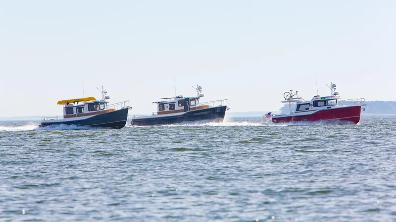Slide: The Image of Three 2024 Ranger Tugs R-31 Sedan Luxury Edition boats cruising on open water. - 30