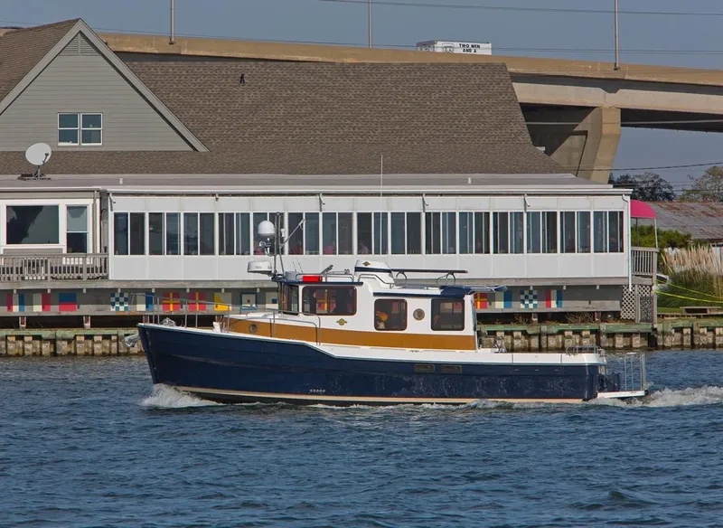 Slide: The Image of 2024 Ranger Tugs R-31 Sedan Luxury Edition cruising near waterfront buildings. - 6