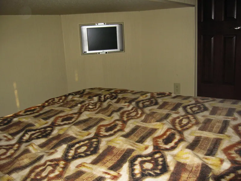 Slide: The Image of Cozy cabin interior of 2004 Skipperliner Dream Chaser Group C with patterned bedding and small TV. - 19