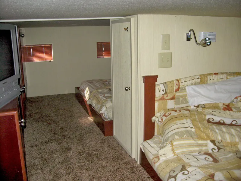 Slide: The Image of 2004 Skipperliner Dream Chaser Group C interior with beds, TV, and carpeted floor. - 20