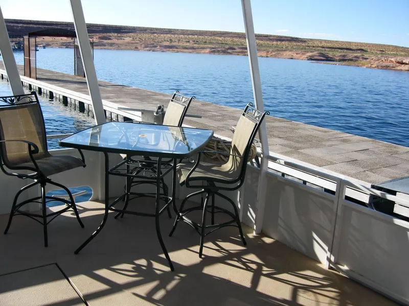 Slide: The Image of 2004 Skipperliner Dream Chaser Group C boat with outdoor seating, docked by a serene lake. - 8