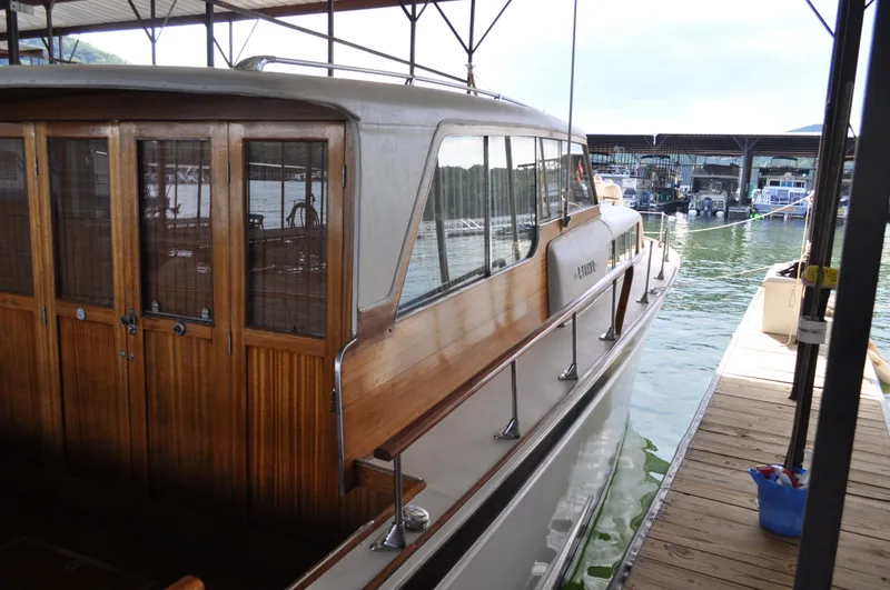 Slide: The Image of 1960 Chris-Craft Roamer docked, showcasing wooden cabin and sleek design. - 12
