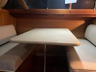 Slide: The Image of 1960 Chris-Craft Roamer interior dining area with cushioned seating and wooden paneling. - 33