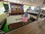 Slide: The Image of 1960 Chris-Craft Roamer boat docked, displaying American flag, wooden deck visible. - 46